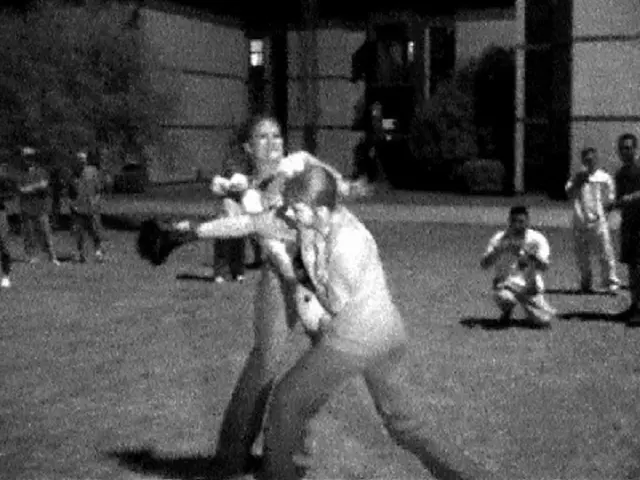 It is a black and white image and in the center we can see the persons performing boxing. In the...