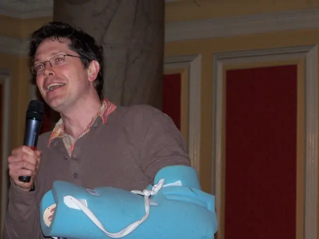 this picture is taken inside a room. There is man standing in the room holding a microphone in his...