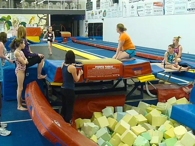 In this image there is a girl walking in a trampoline, around the girl, there are a few people...