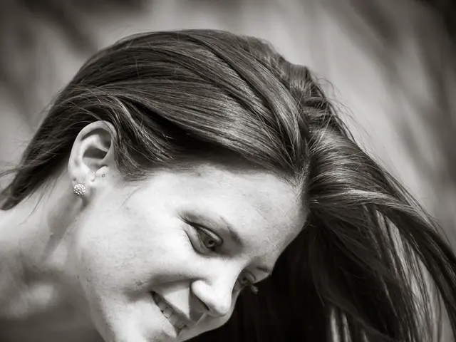 It is a black and white image. In this image we can see a woman smiling. In the bottom right corner...