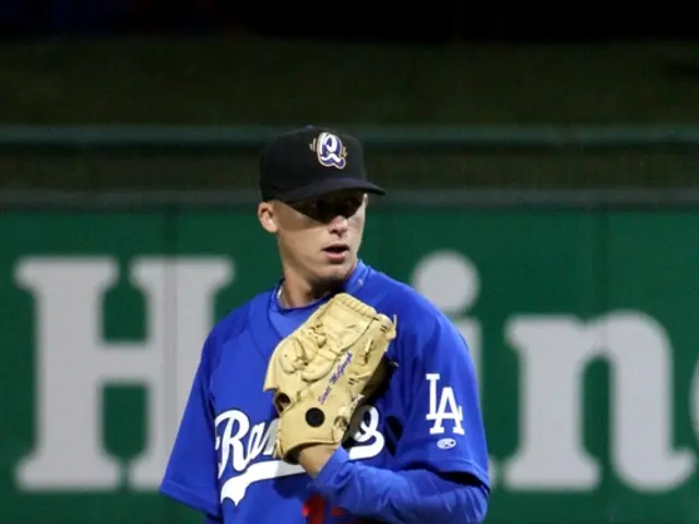 This man wore gloves and looking right side of the image. Far there is a hoarding.