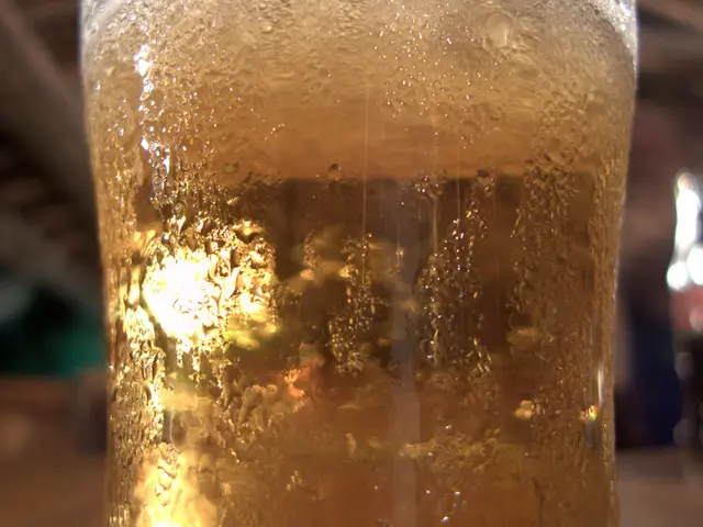 In this image we can see a glass with some liquid. In the background of the image there is a blur...