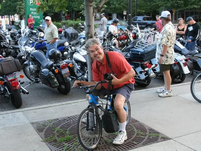 This picture is clicked on the road at a parking lot. The man in the center is sitting on a...