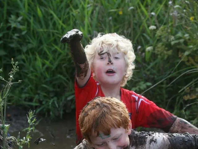 This is the picture of two kids who are standing in the mud water and around there are some plants...