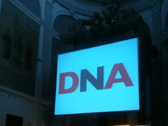 At the bottom of the image there are many people. Also there is a stage. On the stage there is a...