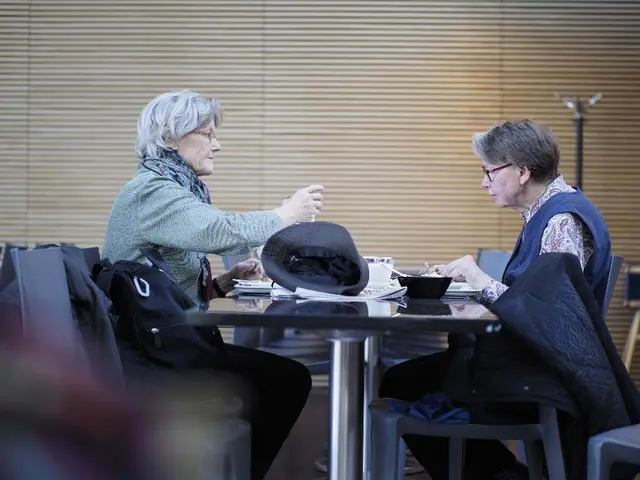 In this picture we can see sitting around the table on two chairs and on the table we have a cap,...