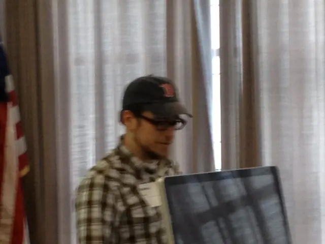 In a picture we can see a man standing is wearing a cap and a spectacle. In front of his there is a...