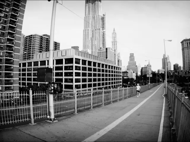 This is a black and white image. In the foreground of the picture there are street lights, cable,...