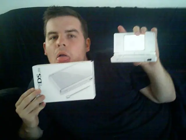 In this image there is a man sitting on a sofa, holding a few objects in his hands, in the...