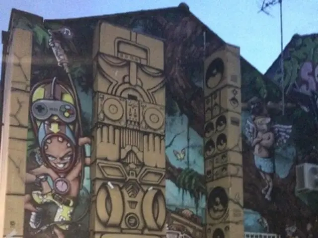 In this picture I can see e building and graffiti on the wall. I can see antenna and a blue sky.