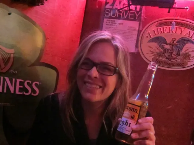 In this picture I can see there is a woman sitting and she is holding a beer bottle in her left...