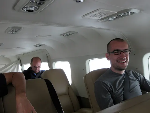 In this image there are persons sitting and in the front the person sitting is smiling and there...