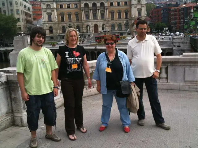 In this image in the front there are persons standing and smiling. In the center there is a...