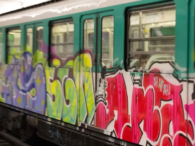 In this picture I can see a train on the railway track, there are two persons inside the train and...