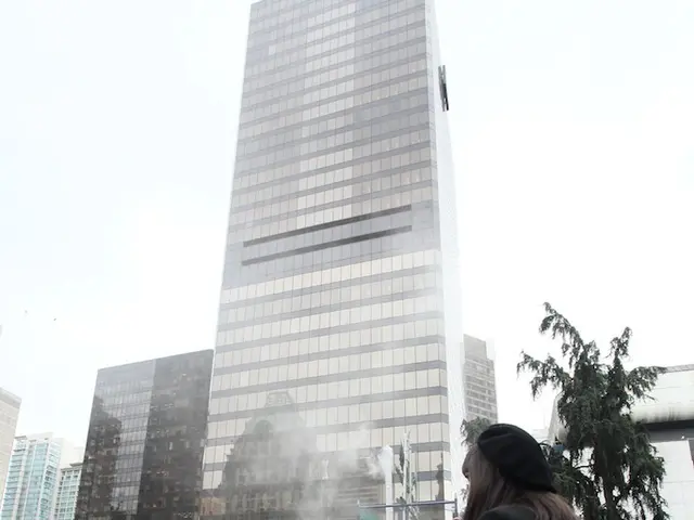 In this image I can see a woman standing on the stage. On the left there are few people. In the...