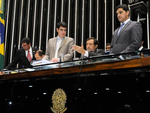 In this picture we can see some people sitting on the stage table. Behind we can see the wooden...