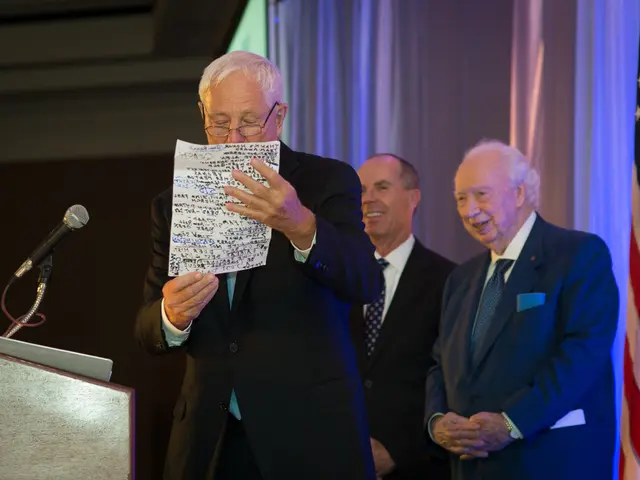 In the image we can see there are people standing and they are wearing formal suit. There is a man...