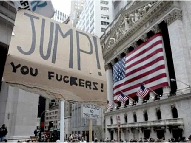 Many people are present. There are placards and sign board. There are U. S flags and buildings are...