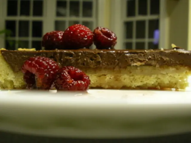 In this picture there is a chocolate pastry with some cherries in the white plate. Behind there is...