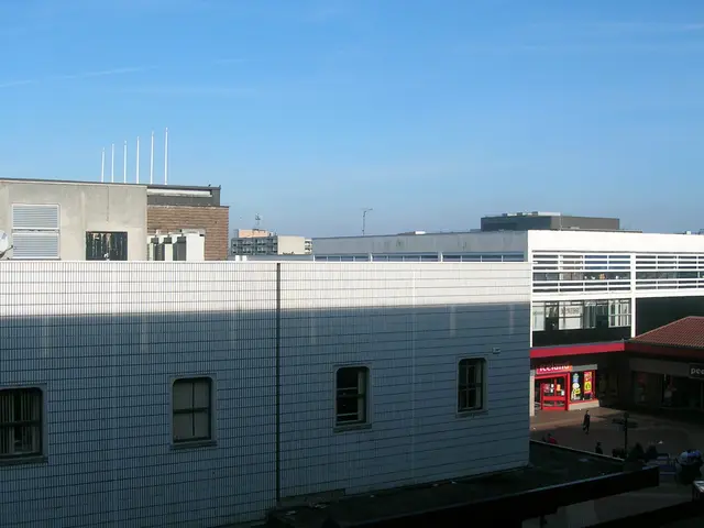In the image there are buildings and stores and in between the buildings there are few people.