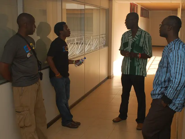 In this image there are four men standing on the floor by looking at each other. The man on the...