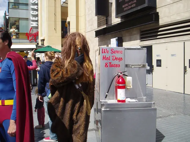 There are many people. Some are wearing costumes. There is a box with something written on that....