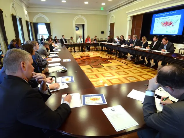 In this image I see number of people who are sitting on chairs and there are tables in front of...