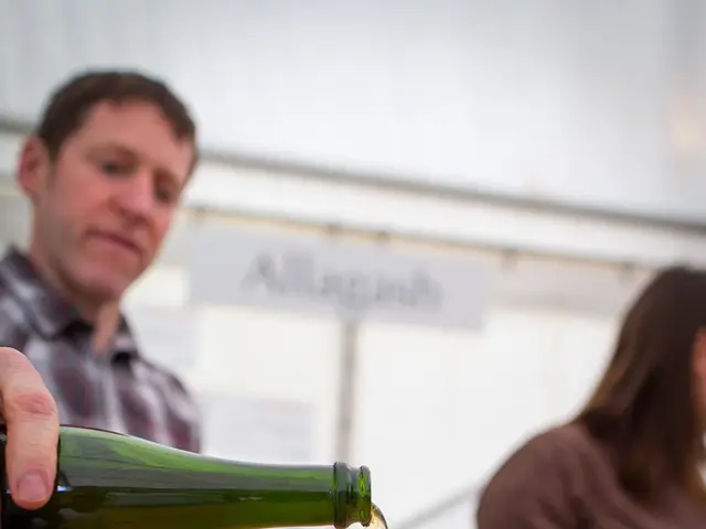 As we can see in the image there are two people. The man who is standing here is holding bottle and...