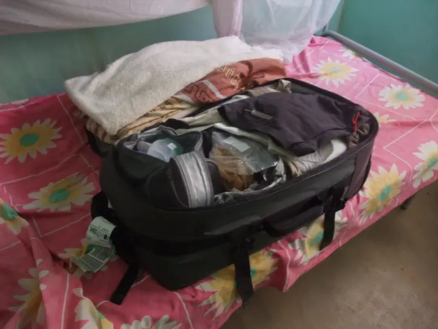 The picture is taken inside a room. There is a bed and a colorful bed sheet is spread on it. There...