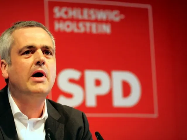 This image consists of a person on the left side. He is wearing black coat. He is talking...