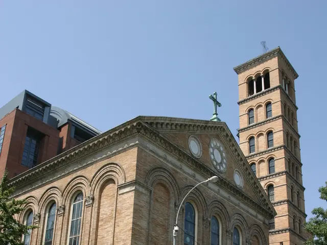 In this picture I can see there are few building and there are poles and trees and there are few...