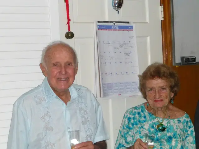 In the picture we can see an old man wearing a shirt is holding a glass and smiling. On the right...