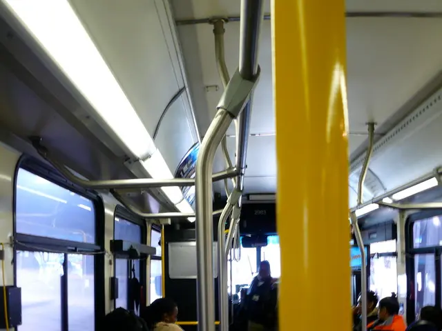 The image is taken inside a bus, the passengers were sitting on the seats and there are some rods...