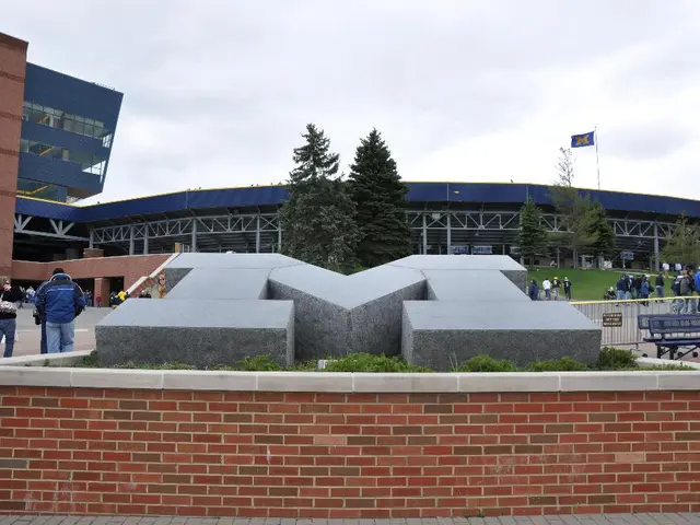 In the foreground of the picture there is a logo and wall. On the left there are people. On the...