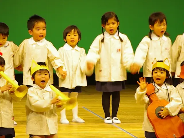 In this image there are kids standing on a stage and they are singing, in the background there is a...