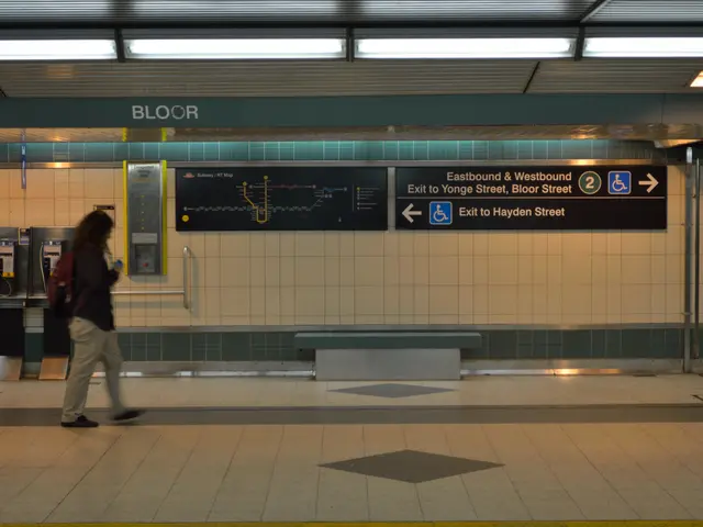 The image shows a woman walking through a subway station at night. She is wearing a bag and holding...
