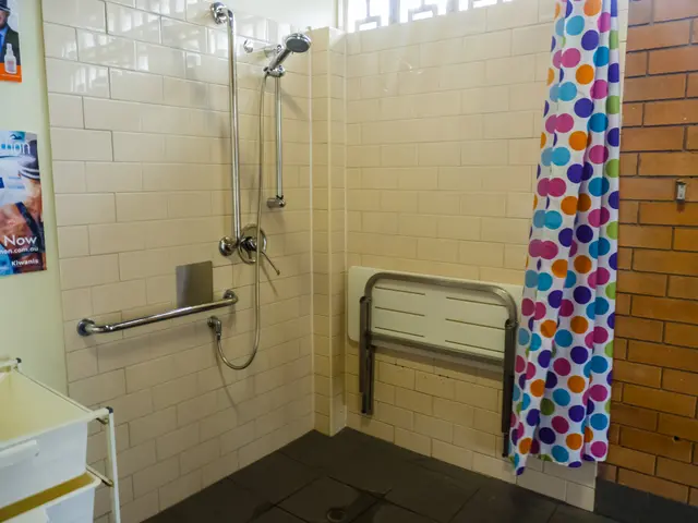 The image shows a bathroom with a shower, handrails, a curtain, a wall with posters, a stand with a...