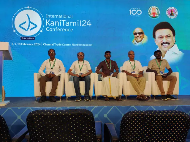 The image shows a group of people sitting on chairs in front of a podium with a microphone, with a...