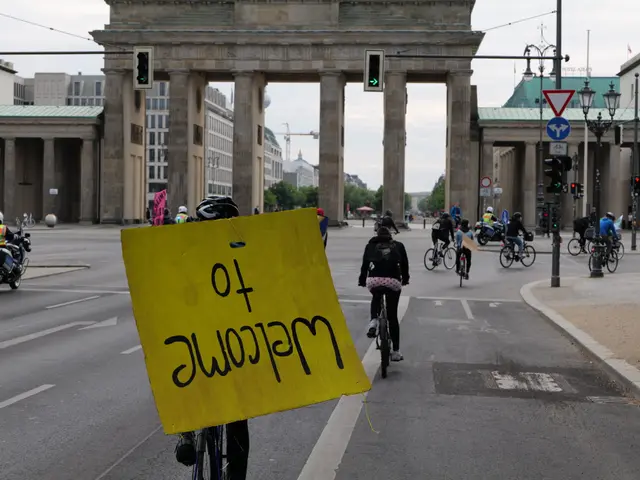 The image shows a group of people riding bicycles down a street in front of the Brandenburg Gate in...