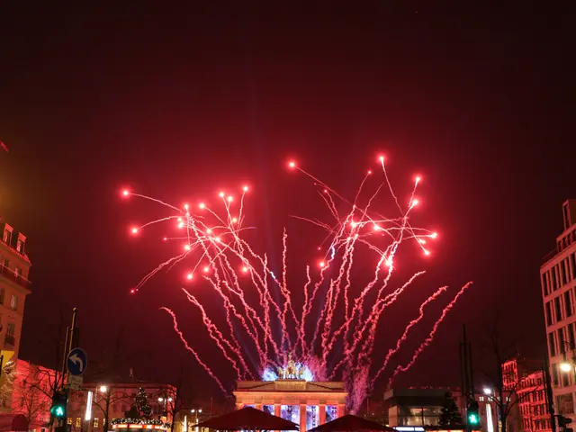 The image shows a city street filled with lots of buildings, trees, light poles, traffic signals,...
