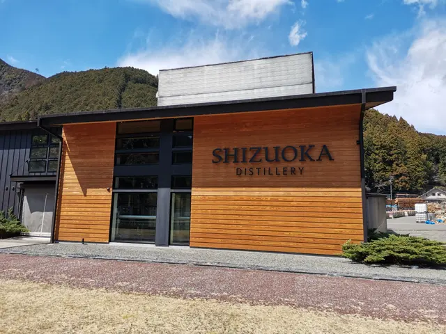 The image shows the Shizuoka Distillery in Japan, with a building featuring glass doors and...