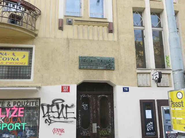 The image shows a building with graffiti on the side of it, a pole with a sign board, windows, a...