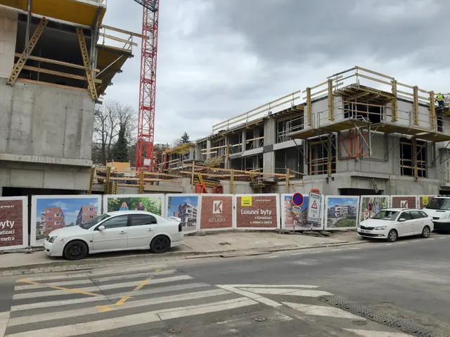 The image shows a construction site with cars parked in front of a building under construction. The...