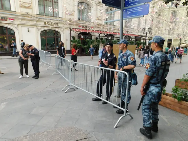 The image shows a group of police officers standing in front of a crowd of people, some of whom are...