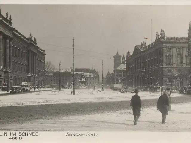 The image shows two people walking down a snowy street in Berlin, Germany. The street is lined with...