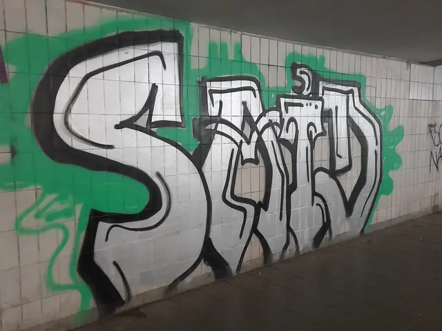 The image shows a wall with graffiti on it in a subway station, with a floor at the bottom and a...