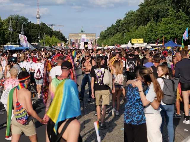 The image shows a large crowd of people walking down a street in Berlin, Germany. Many of them are...