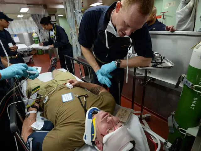 The image shows a man laying on top of a gurney in a hospital room, surrounded by a group of people...