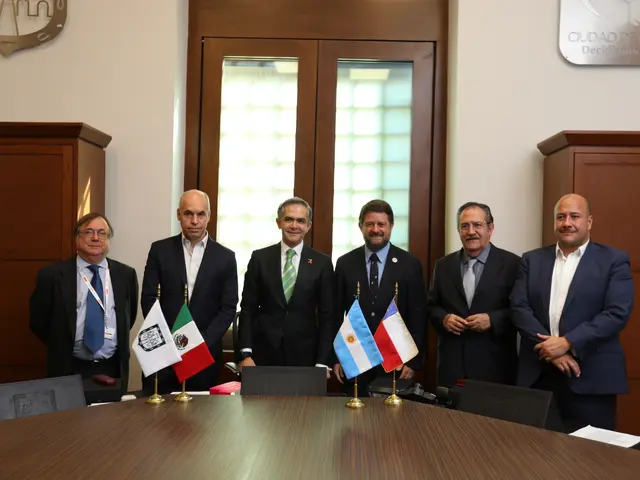 The image shows a group of men standing around a table with flags, papers, and other objects on it....