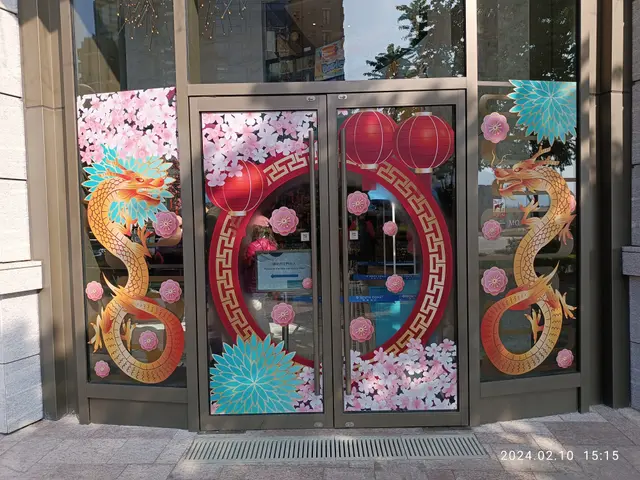 The image shows a glass door with Chinese New Year decorations on it, reflecting the trees,...